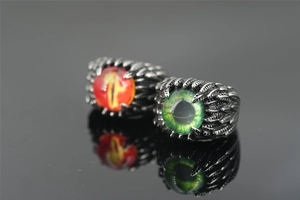 Macro view of gothic dragon eye rings with red and green pupils on black mirror