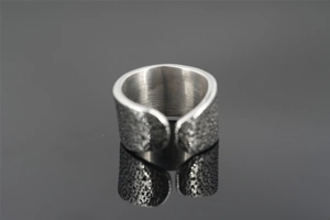 Detail of wide silver ring featuring textured surface and adjustable open band design