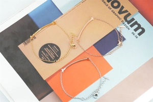 Detaillierte Makroansicht von drei minimalistischen T-förmigen Smile-Armbändern in Gold und Silber
