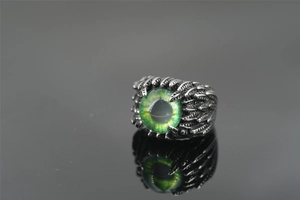 Macro view of vintage punk ring featuring a green dragon eye and feather textures