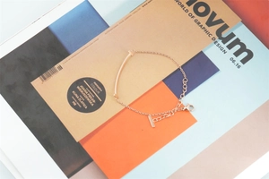 Detail eines roségoldenen Smile-Armbands, das auf einem modernen Designmagazin liegt