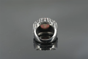 Detail view of vintage feather ring with red cat-eye stone on reflective background