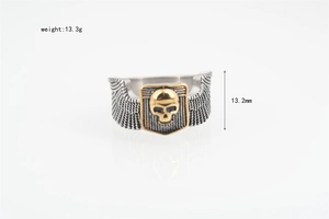 Detailed macro view showing the golden skull relief and engraved wings on a punk steel ring