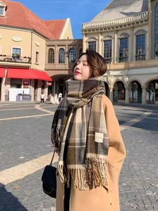 Detailed view of the thick brown plaid winter scarf with fringe ends and woven label