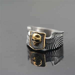 Punk style men's silver and gold skull ring with feather textures on black mirror