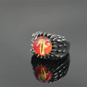 Gothic dragon eye ring with feather texture and orange pupil stone on reflective surface