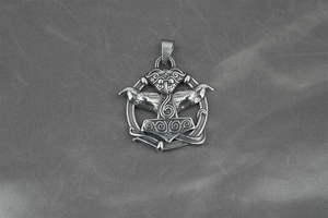 Macro shot of vintage silver Mjolnir pendant with detailed Odin raven engravings