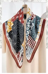 Détail d'un foulard en soie à motif chevrons et géométrique drapé sur un pull-over