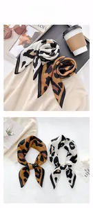Close-up of leopard print square scarves with silk texture on beige knitwear background