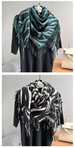 Detail of soft cashmere-like scarf with zebra print and thick fringed edges in black and white