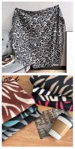 Detail of leopard and zebra print scarves with fringed edges on a wooden table