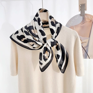 Classic leopard print silk scarf styled in a knot over a beige knit top for a retro look