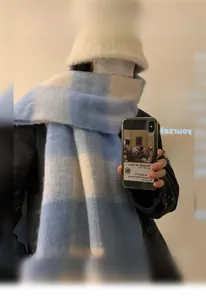 Detail of blue and white checkered winter scarf with white plush bucket hat