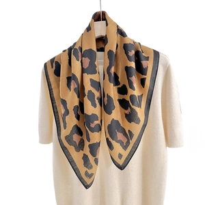 Vintage leopard print square scarf in camel and brown tones on a wooden hanger