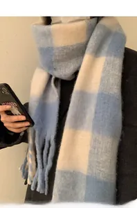 Detail of blue and white checkered scarf with thick knit texture and fringe tassels