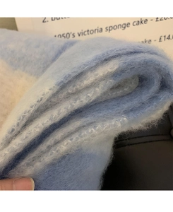 Close-up of soft blue and white checkered scarf with thick mohair-like knit texture