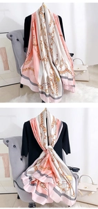 Detailansicht eines Seidenschals in Rosa und Creme mit goldener Kette und Gürtelmuster