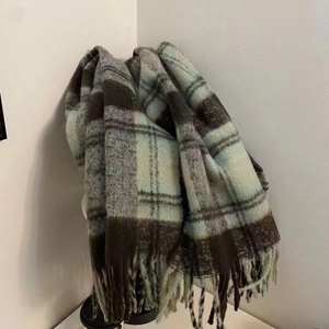 Detailed view of mint green and brown plaid scarf with long thick tassels