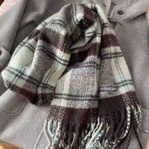 Detail of mint green plaid scarf with soft fringe on grey coat, winter cashmere feel