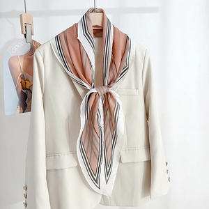 Elegant striped silk-like diamond scarf in pink and black on a beige blazer