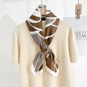 Elegant earth-tone printed silk scarf featuring abstract geometric patterns on a beige knit top