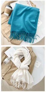 Detail view of solid color tassel scarves in peacock blue and cream with soft texture