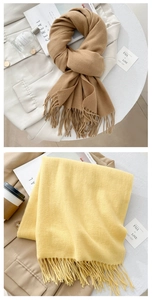 Close-up of camel and yellow cashmere-feel scarves with fringe details and soft texture
