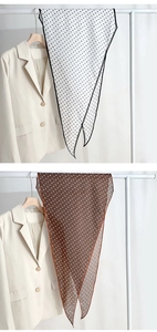 Close-up of lightweight polka dot silk scarves in black and brown hung on minimalist hangers