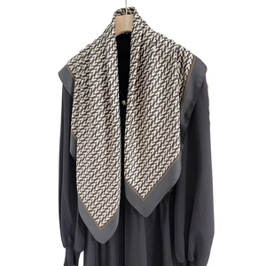 Elegant silk scarf with beige and black V-pattern print hanging on a black dress