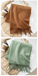 Detail of caramel and sage green cashmere-feel scarves with soft fringe tassels