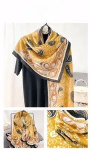 Close-up of yellow paisley print shawl scarf with intricate geometric patterns and black trim