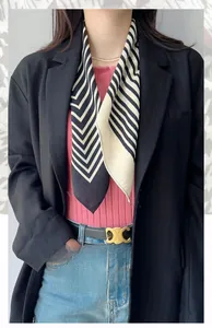 Close-up of black and white herringbone square scarf styled with a black blazer