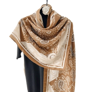 Caramel and beige cotton linen scarf with mandala patterns on a display stand
