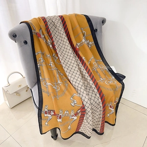 Elegant mustard yellow scarf with classic chain and bit pattern on a luxury grey chair