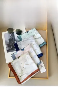 Detailed stack of imitation silk square scarves with floral prints in a gold tray