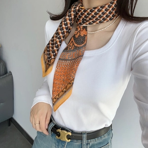 Silk square scarf featuring houndstooth and orange paisley patterns worn by a model