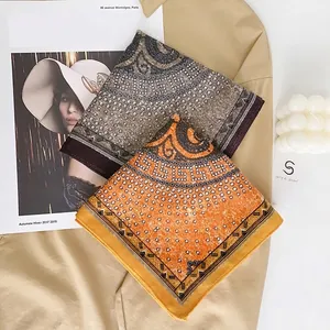 Brown and orange silk scarves with Greek key patterns and rhinestones on a trench coat
