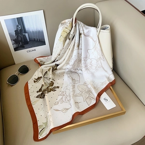 Elegant rose floral print silk square scarf in beige and brown draped over a handbag