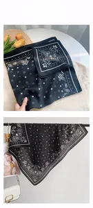 Macro detail of black square scarf with white paisley pattern and star motifs on silk fabric