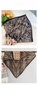 Detail eines eleganten Seidenschals mit goldenem Paisleymuster und gewelltem Rand