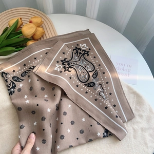 Brown paisley silk square scarf with star patterns displayed on a white table with tulips