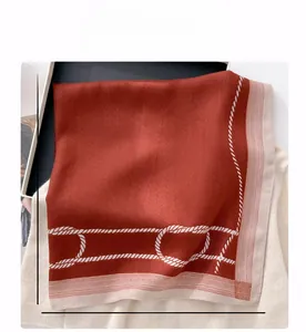 Detail of a deep red 68cm silk square scarf with nautical rope patterns on soft knitwear