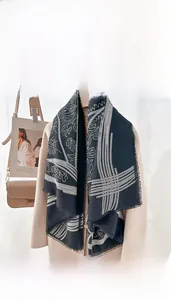 Detail of black printed wool shawl with geometric patterns and fringe edges on a beige coat