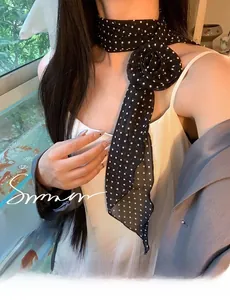 Détail d'un foulard fin à pois noir et blanc avec une grande broche de rose en tissu