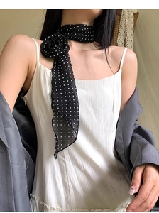 Détail d'une écharpe noire à pois fins avec fleur 3D stylisée sur un blazer gris chic