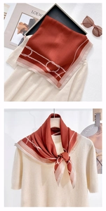 Detail of rust red silk square scarf with beige border and white rope chain pattern texture