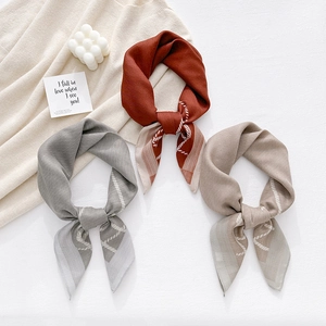 Elegant herringbone silk neck scarves in red, grey, and camel on knitted fabric