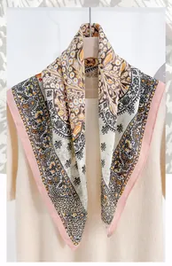 Detailed view of cream floral herringbone silk scarf draped on beige knitwear