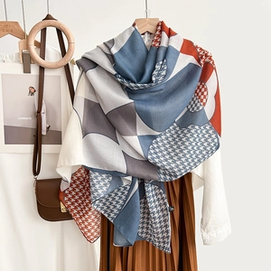 Elegant geometric silk scarf with houndstooth and color-block pattern hanging on a hanger