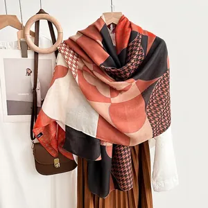 Elegant orange and beige geometric houndstooth scarf displayed with a stylish handbag